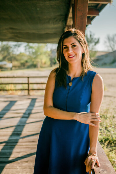 Young female CFO, wearing a blue dress and smiling in the daylight