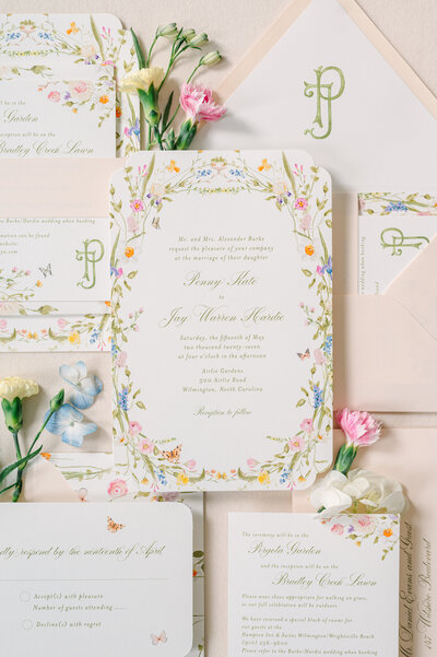 A garden wedding invitation with bright watercolor flowers and butterflies, belly band, watercolor monogram