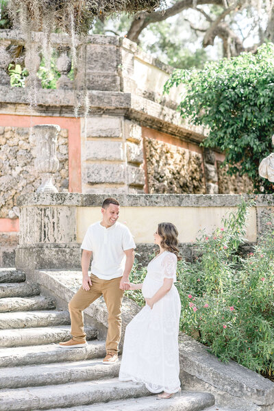Couple looking at each other while standing in Vizcaya in Miami during their maternity shoot with Ivanna Vidal Photography