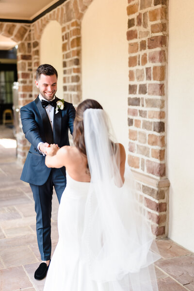 A bride in a flowing white dress and her husband in a black suit hold each other and smile at the camera