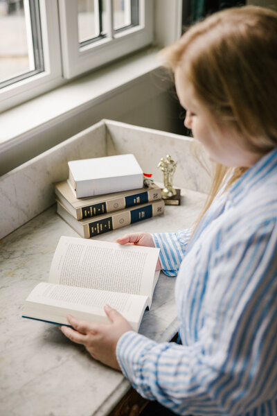 Woman in a blue and white striped top flipping through a book at a desk