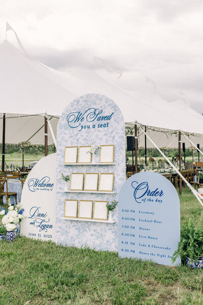 Luxury wedding seating chart and schedule display with blue floral signage by Seventh and Anderson for outdoor tented Montana wedding
