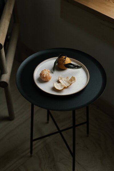 A peeled orange sitting on a black side table. The photo shows the importance of prioritizing your physical health through a balanced diet.