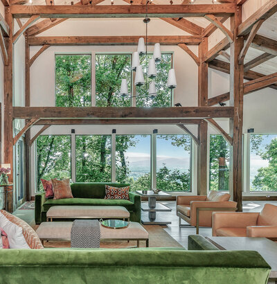Image of open concept living space overlooking Owens Crossroads with exposed beams, velvet green seating. mountain view