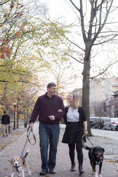 A couple walking arm in arm as they walk their dogs 