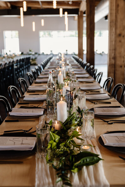 A long square reception table with flowers and candles on it.