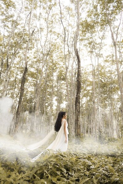 Woman in a white gown walking through an enchanted woods