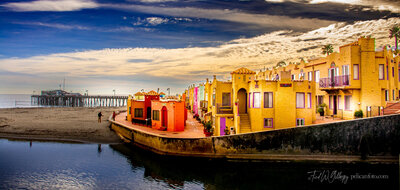 Venerable Capitola Venetian Hotel illuminated in late afternoon’s brilliant light with Capitola Wharf in horizon.
