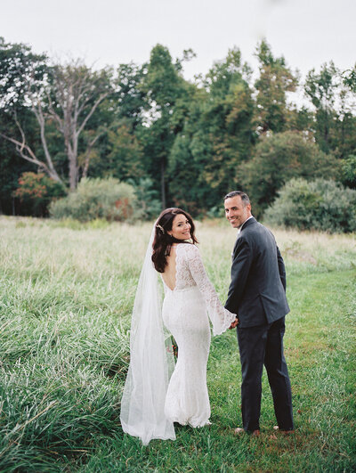 Photo of couple on a field looking back towards the camera 