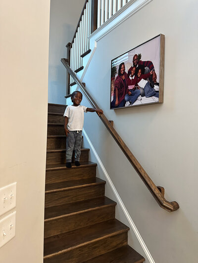 finished portrait artwork displayed on wall above stairwell youngest son smiling while showing it off portrait studio charlotte nc