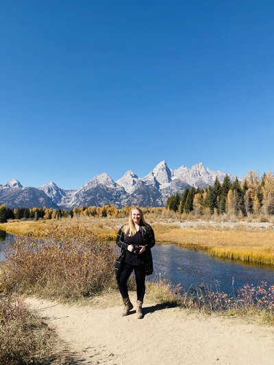 Jessica Nicole Photography smiling holding her camera at Schwabachers Landing in Jackson, Wyoming. Ready to photograph your Colorado wedding.