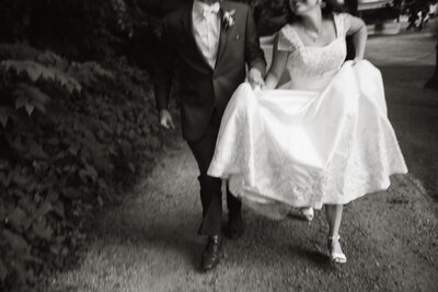 Black and white photo of a bride and groom walking together after their wedding ceremony in Michigan City, Indiana, captured by Rainstorm Photo & Video in an emotive, documentary style.