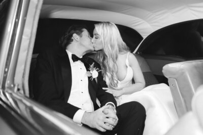 sexy bride and groom kiss in the back of a car for their wedding reception getaway at the Osage House wedding in Bentonville Arkansas