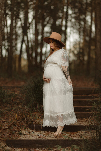 Pregnant mama in white dress in the woods by Lawrenceville Maternity Photographer