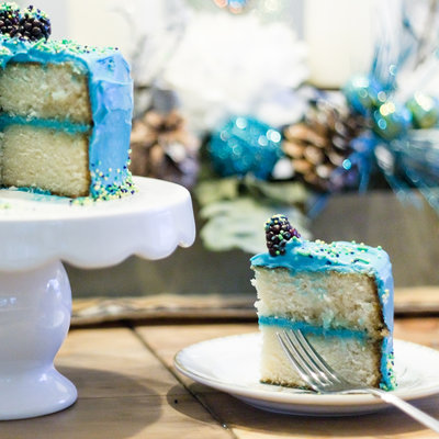 A slice of white cake with blue icing as photographed by Ashley Gregoire Photography