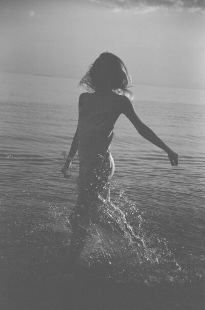 Black and white photo of woman freely walking on the shoreline