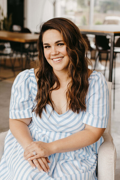 woman with dark hair and white and blue stripped derss sitting