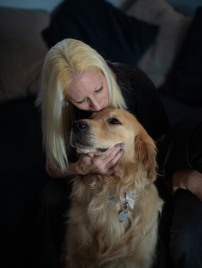 AJ gently kissing her dog's head, symbolizing the deep love and bond shared between pets and their families, reflecting the compassion behind Nature's Way Pet Aquamation in Lansing, Michigan.