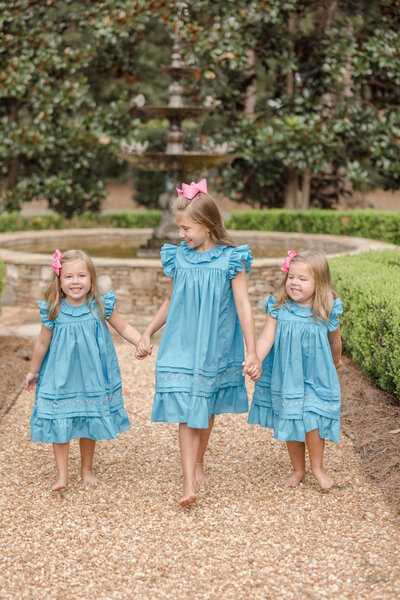 Three young girls holding hands and walking down pebble path - Maternity Photographer Greenville SC