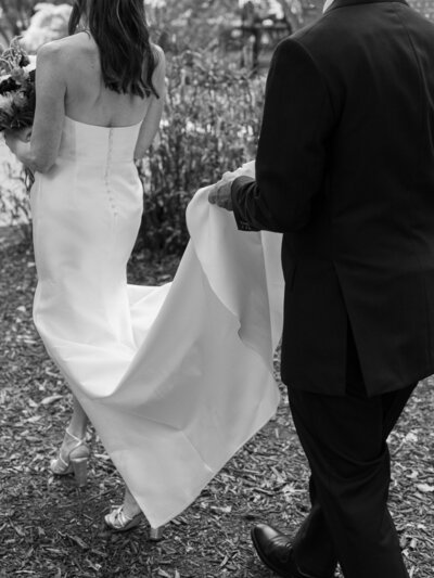 A closeup of a bride standing close to her bridesmaids with large, colorful bouquets of peonies, anemones, and other flowers.