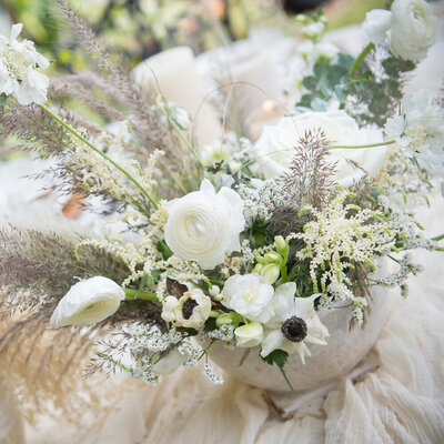 white and cream colored bouquet with flowers and feathers
