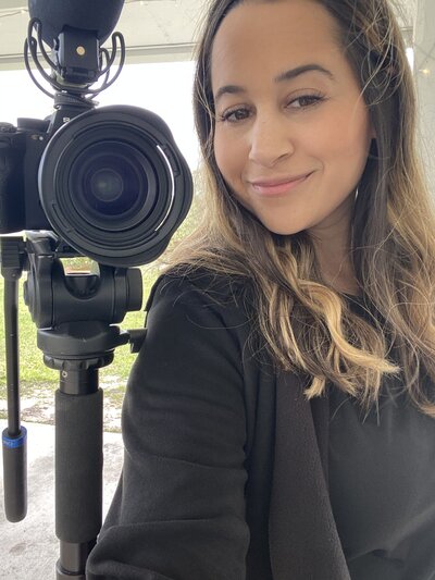 woman smiling while standing next to camera