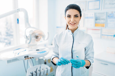 A female dentist smiling at the camera in an operating room.