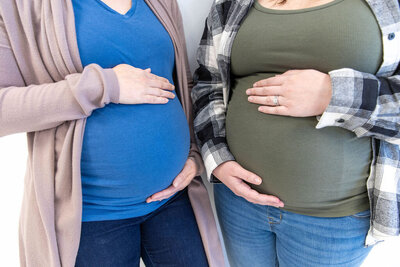 Two pregnant women gently holding their bellies