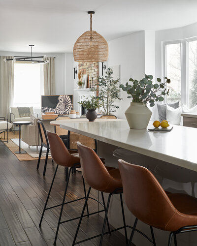 A spacious white kitchen island lined with elegant brown chairs.