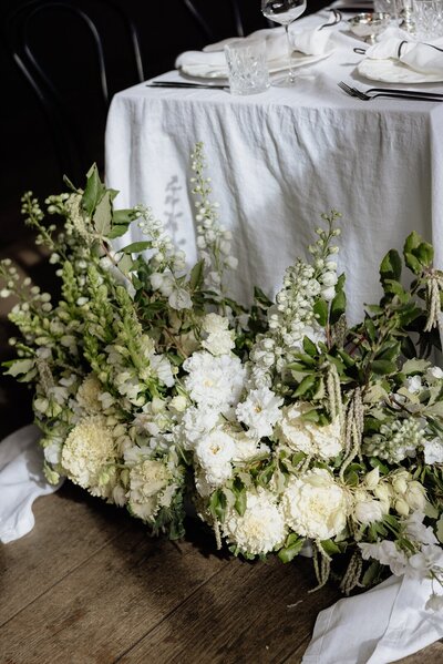 White wedding flowers around a white reception table