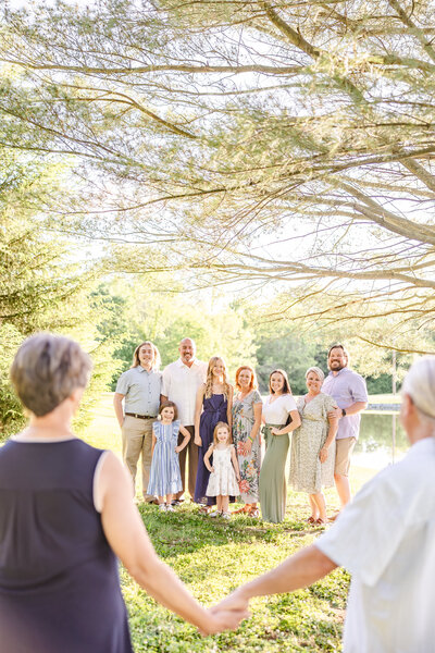 Grandma and Grandpa hold hands looking at family, the legacy they created, while the rest of the family is gathered looking and smiling at them.