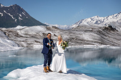 Newlyweds pop champagne and  have a toast  high up on a glacier in Alaska.