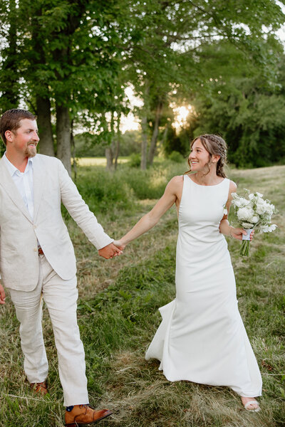 Couple holding hands and walking together on their wedding day at sunset