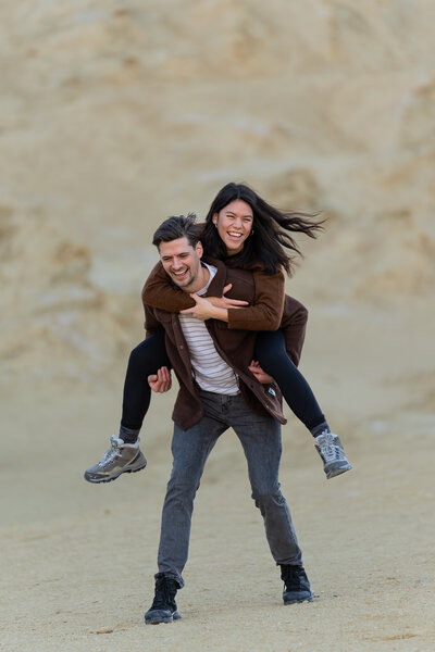 A person on their partner's back as they both smile