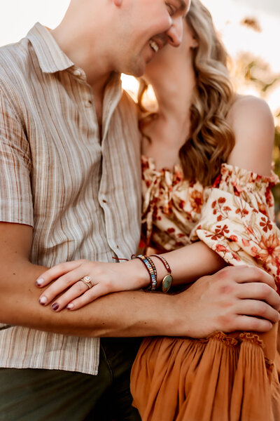 Mom and Dad have a moment and whisper and snuggle together with their hands on each other during a family photoshoot by Kansas City photogrraphers.