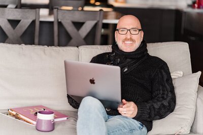 Lifestyle brand image of small business owner working from his couch, with his coffee in front of him