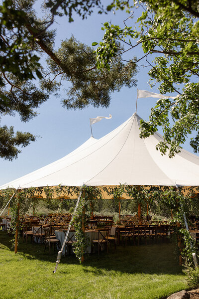 Sperry tent set up for a wedding reception on private property, surrounded by lush greenery.
