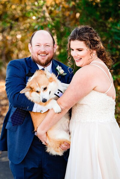 First Look with their dog! Bride and groom holding corgi for a photo