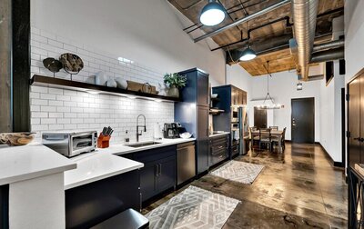 Industrial modern kitchen with view of the dining area in this three-bedroom, two-bathroom vacation rental condo in the historic Behrens building in downtown Waco, TX.