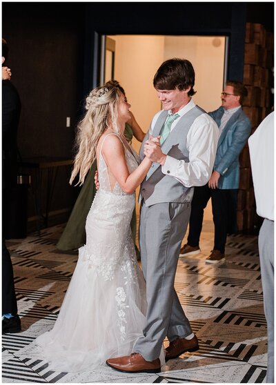 bride and groom dance together at their reception smiling at each other and having a good time