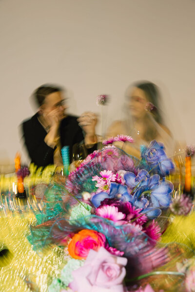 A wedding couple sitting at a colorful reception table.