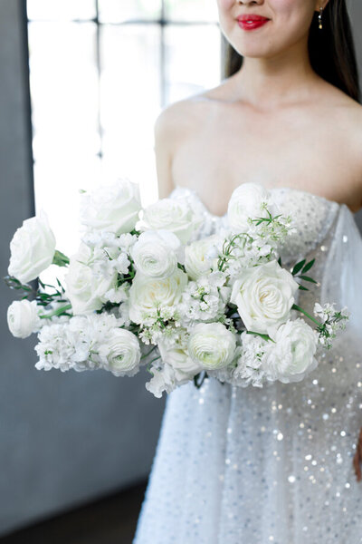 Model in sparkly wedding dress holding white garden bouquet at Utah editorial styled shoot at White Space Studios.