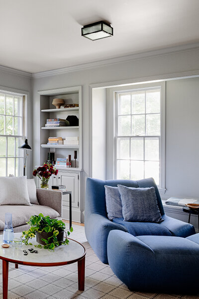Full service interior design Boston renovated a historic Hingham family room with traditional architecture, modern furnishings, and a bold blue chair.