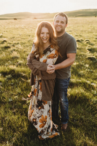 Morgan and her husband smiling for a photo in their cattle pasture.