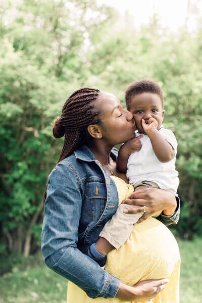 A pregnant mother kisses her young son on the cheek while holding him close in an outdoor setting – Family Autism Support Coach at Chantal Hewitt Coaching