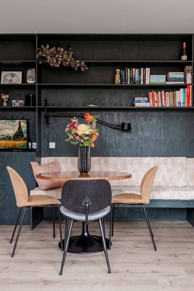 Stijlvol ingerichte eetruimte in een vakantiehuis, met een moderne houten tafel en boekenplanken voor een warme en uitnodigende sfeer. Ideaal voor Airbnb en vakantieverhuurpromoties.