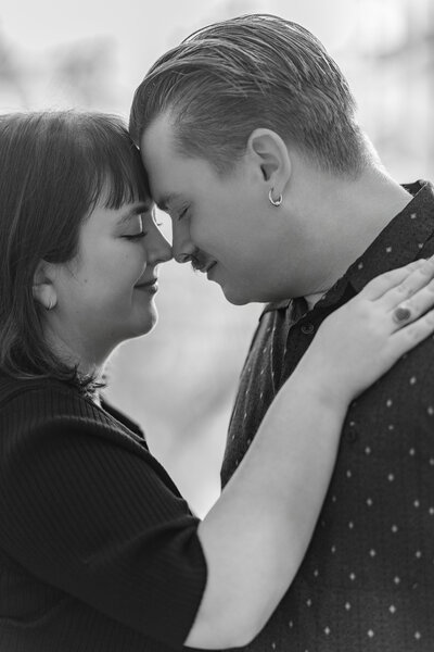A couple leans in lovingly for an engagement picture. Black & white photo by Claire Katan, an Omaha photographer.