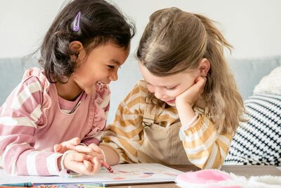 Two children coloring together at table | Rooted Within collaborative learning and family guidance support
