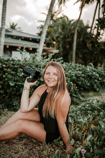 Sierra the owner of Sierra Bertini sitting on a beach in Maui smiling while getting her photo taken