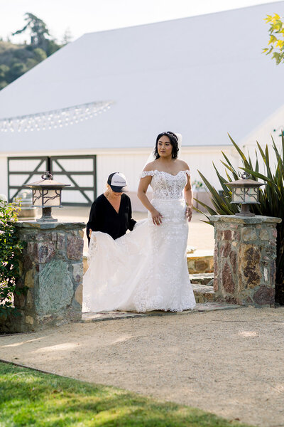 Sandcastle Celebration wedding planner fixes brides dress at white barn in san luis obispo